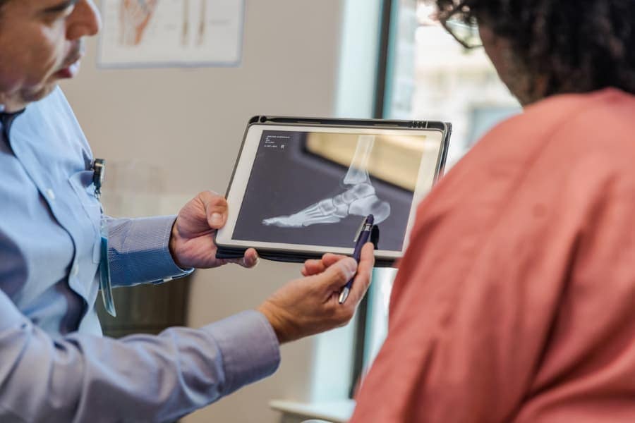 Podiatrist discussing X-ray on tablet with patient in examination room 