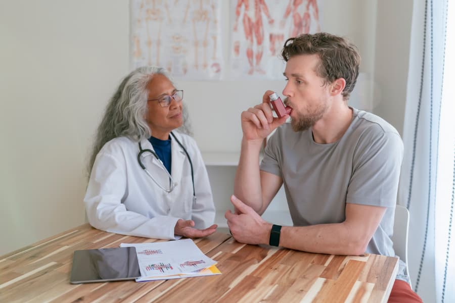 Patient uses inhaler while physician observes