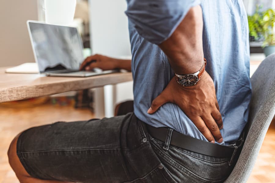 Man sitting and rubbing back in pain