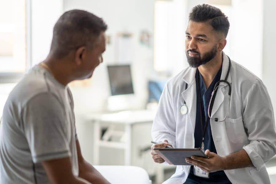 Patient discussing risk and cancer screenings with physician in examination room