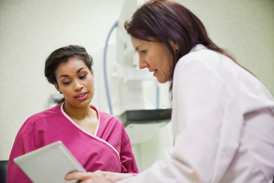 Physician explaining cancer screening to patient wearing radiological protection 