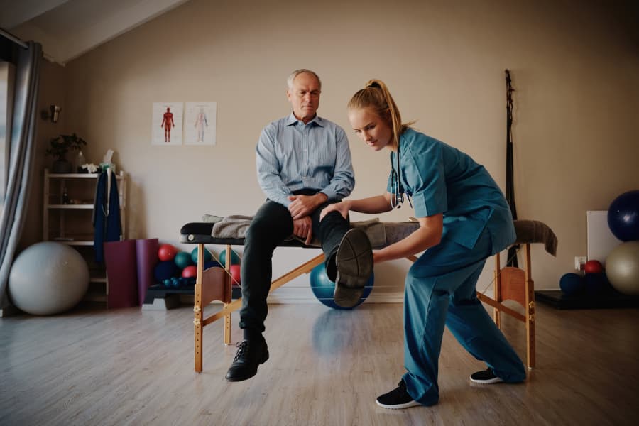 Female Physician Helping A Man Exercise His Knee