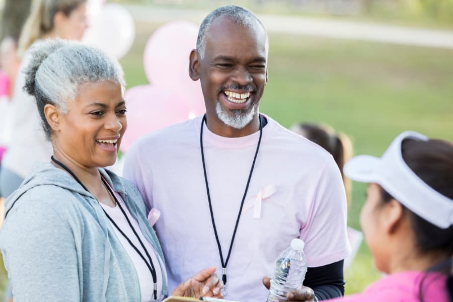 A couple talks with a volunteer at a breast cancer awareness fun run.