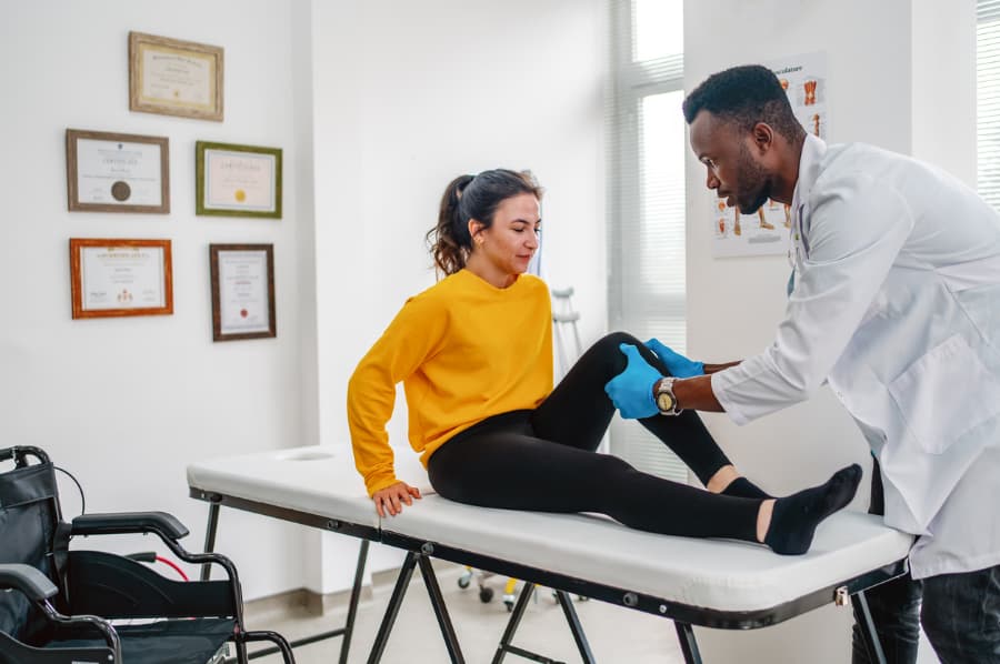 A physical therapist treats a patient with an injured knee.