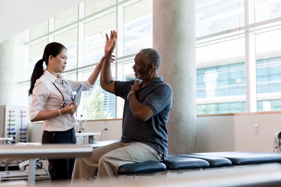 An orthopedic specialist helps a patient test range of motion in his arm.