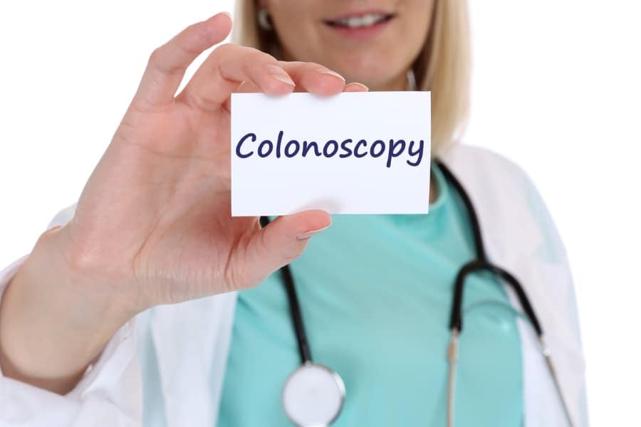 A physician holds up a card with the word “colonoscopy.”