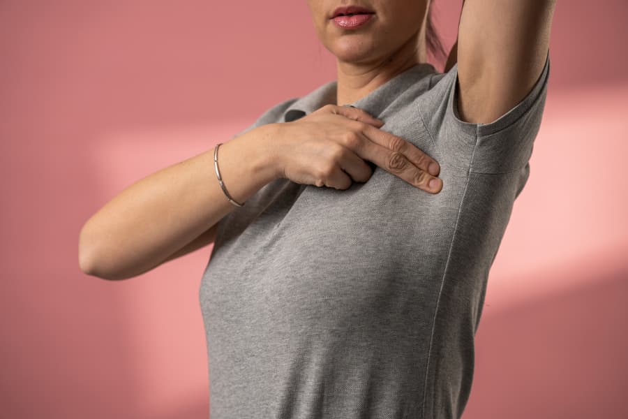 woman examining under her armpit to detect lumps or signs of breast cancer