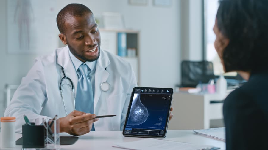 Doctor Showing Mammography Test Results to a Female Patient on a Tablet Computer in a Health Clinic