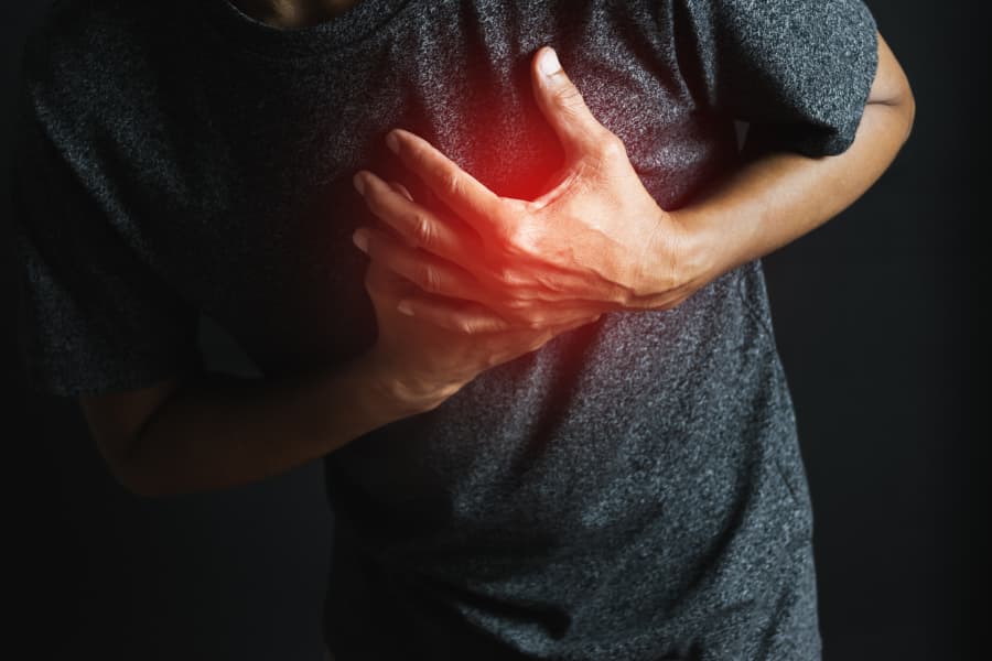 Closeup of man clutching chest with red overlayed to indicate area of pain