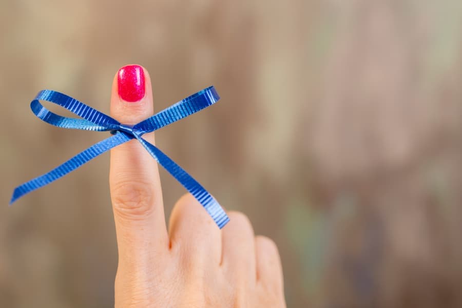 Blue colon cancer ribbon tied around patient’s finger