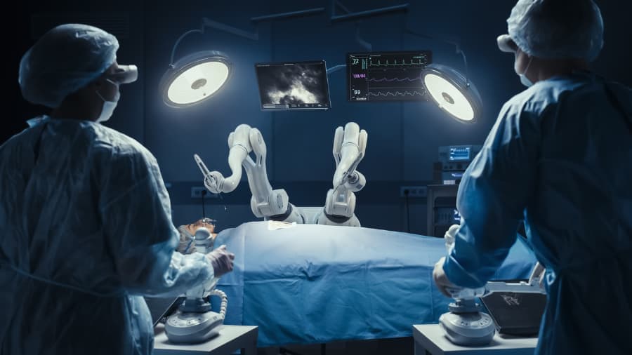 Two surgeons in operating room looking at robotic machine above patient
