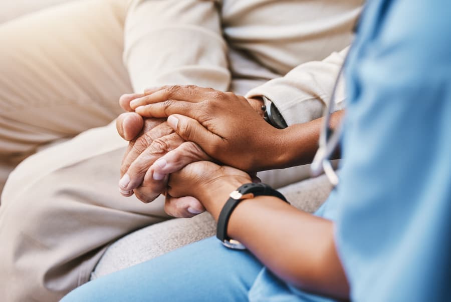 Medical professional holding hand of patient with cancer