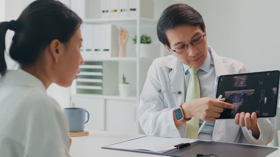Physician sitting behind desk showing patient results of lung cancer screening