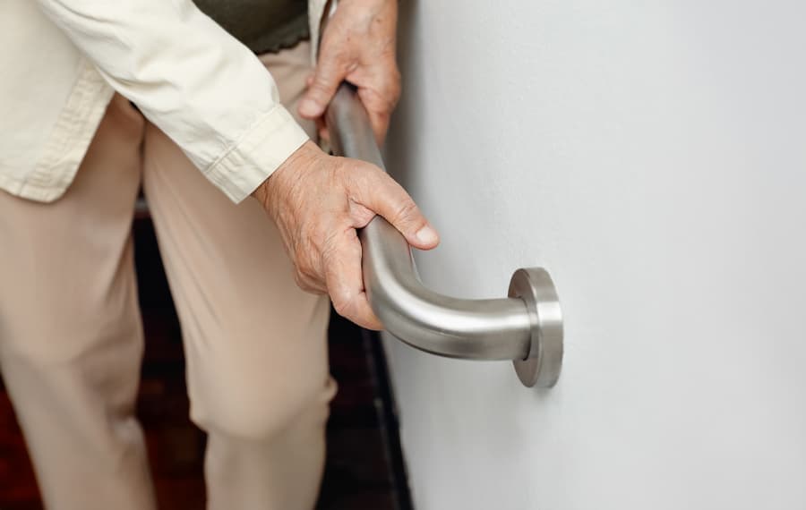 Elderly person using handrail for support