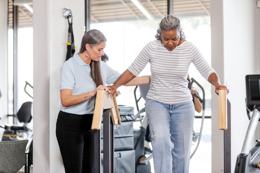 Physical therapist helping elderly Parkinson’s patient